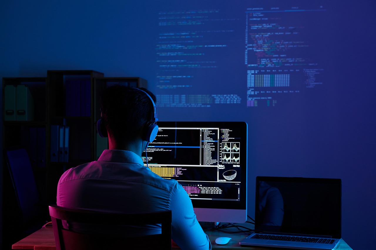 Software developer at workstation with multiple monitors
