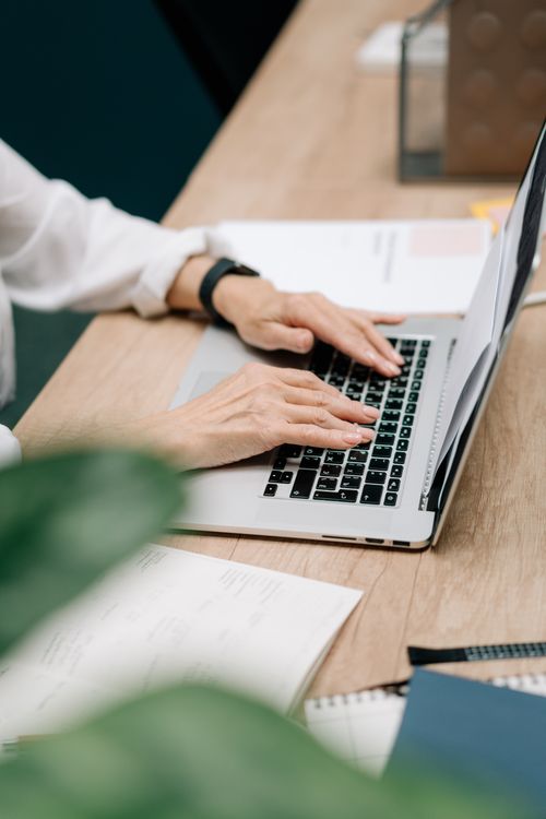 A professional reviewing work on a laptop in a bright modern workspace