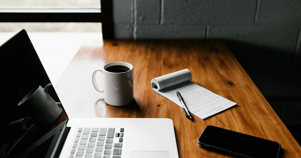 Laptop and notebook on a wooden desk in a quiet writing workspace