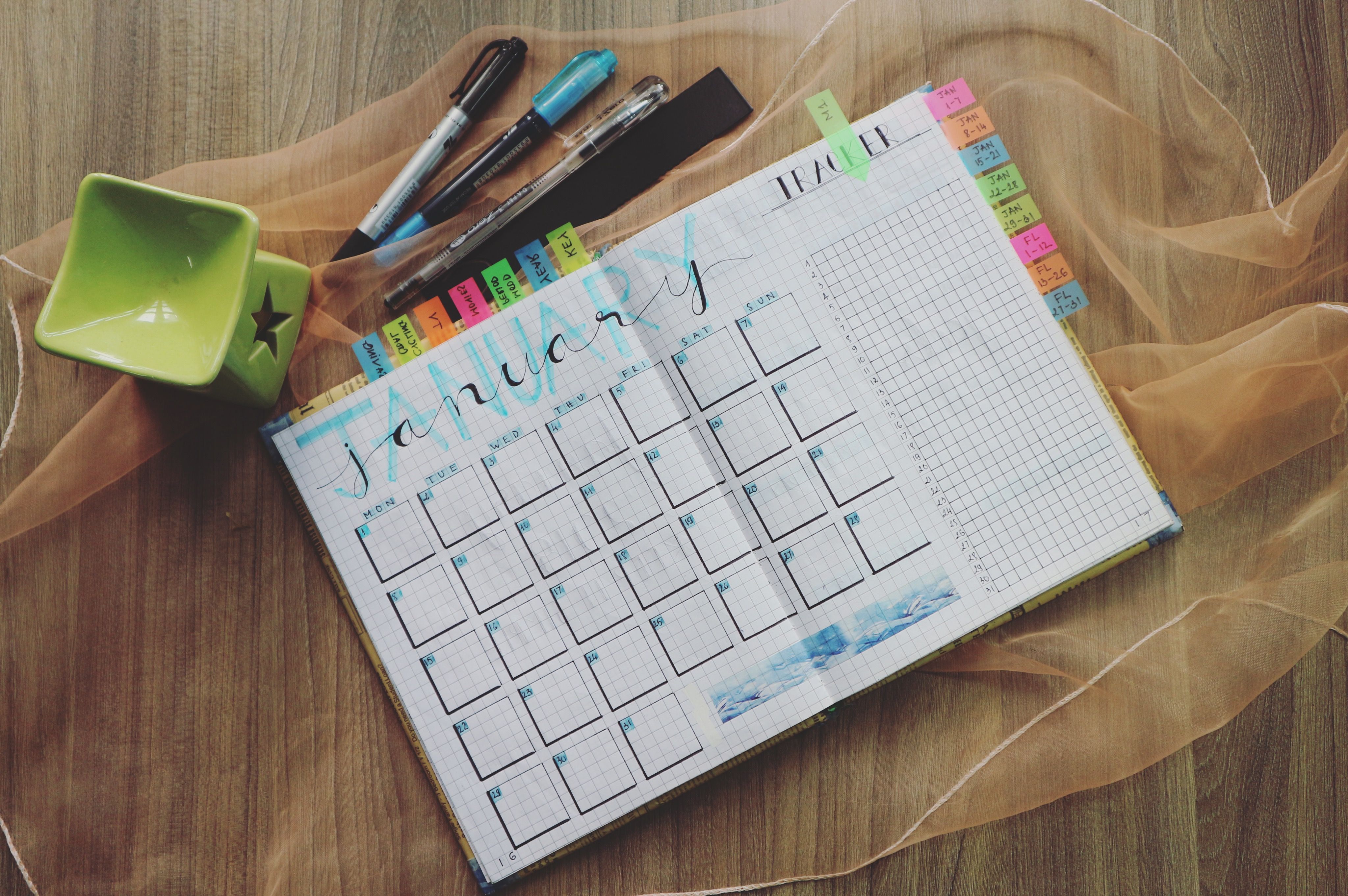 Desk with a monthly planner, notebook, and laptop used for scheduling blog content