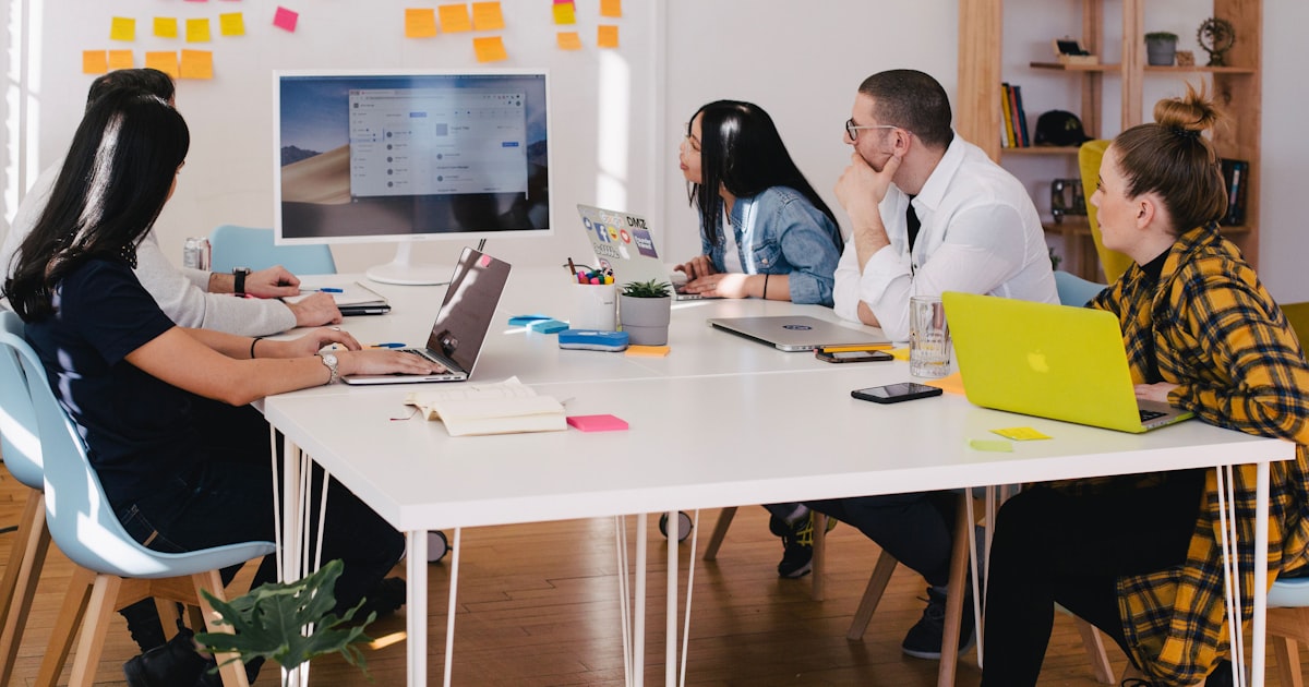 A diverse team collaborating around a laptop in a modern office workspace