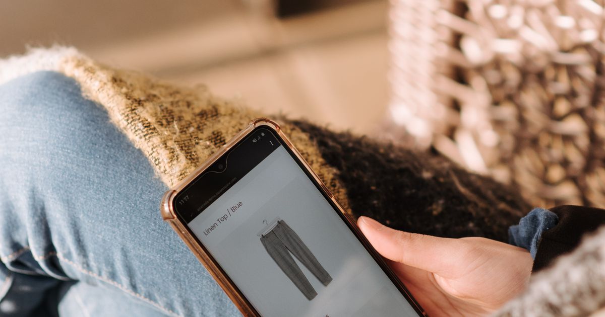 Woman browsing fashion products on smartphone while shopping online from home