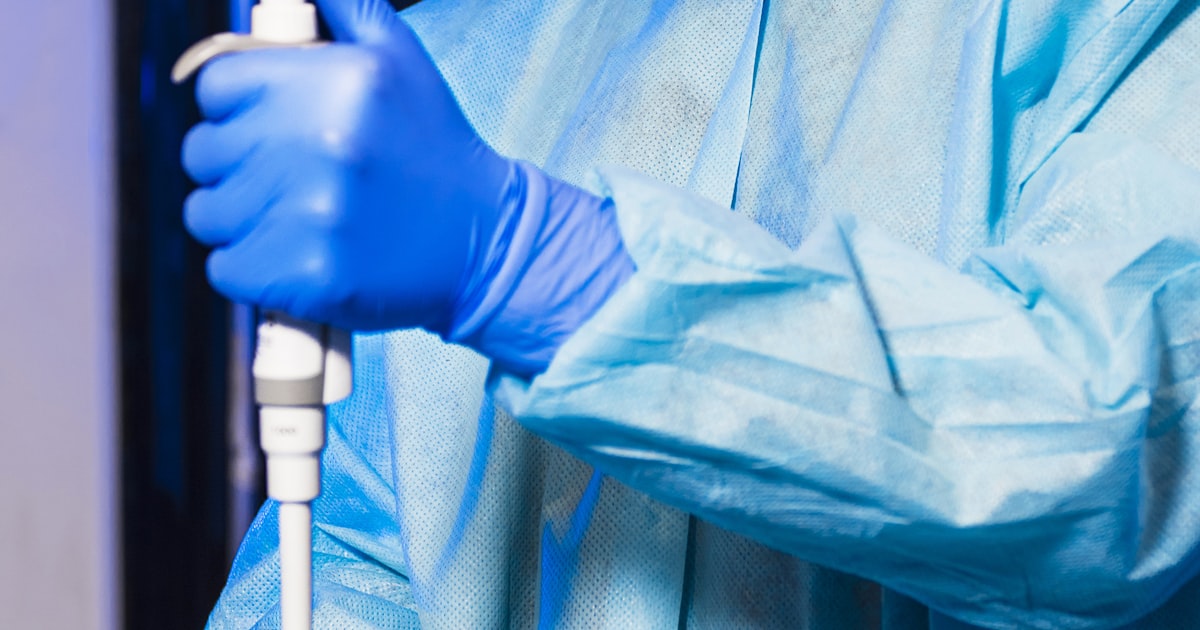Scientist in a white lab coat running a chemical experiment with test tubes and solutions