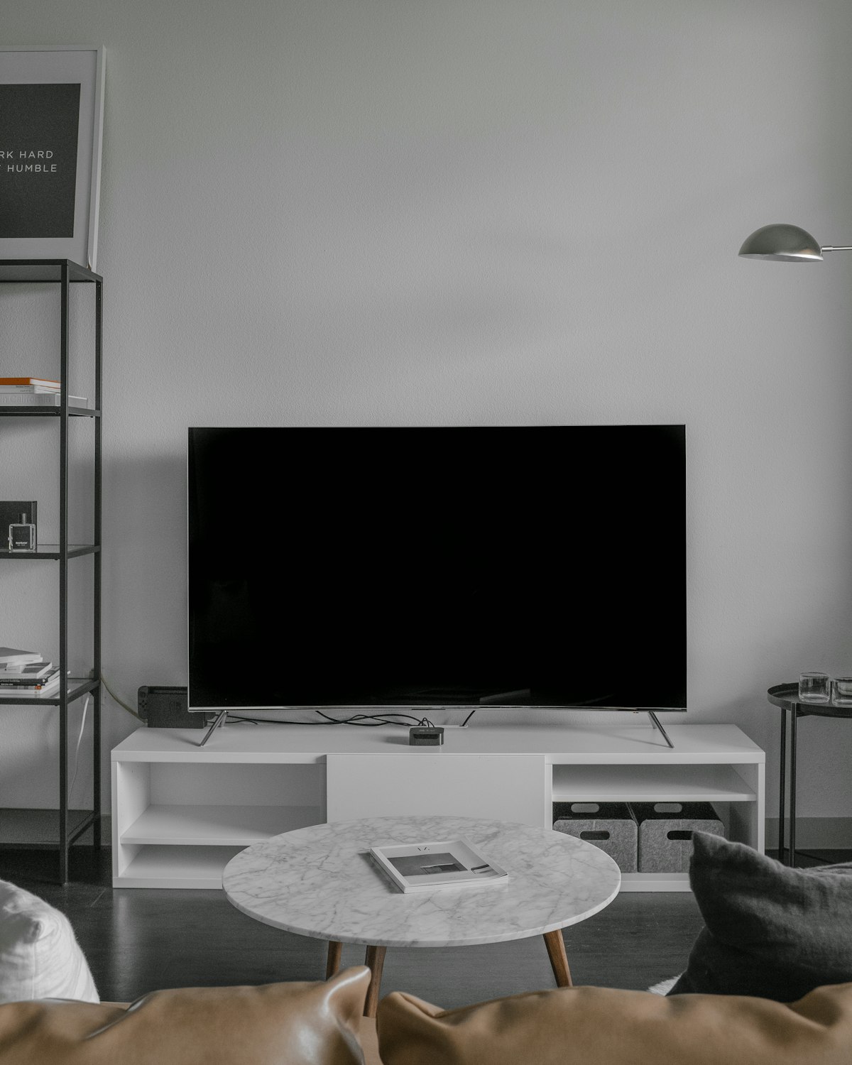 Person hält eine TV-Fernbedienung und richtet sie auf den Fernseher