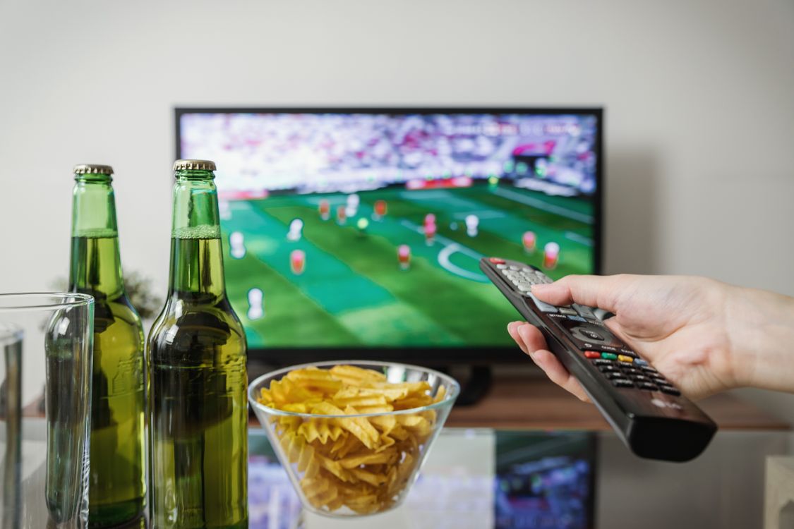 Person mit Fernbedienung vor einem Fernseher im Wohnzimmer