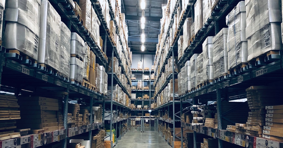 Warehouse interior with tall shelving units filled with boxes and pallets ready for distribution