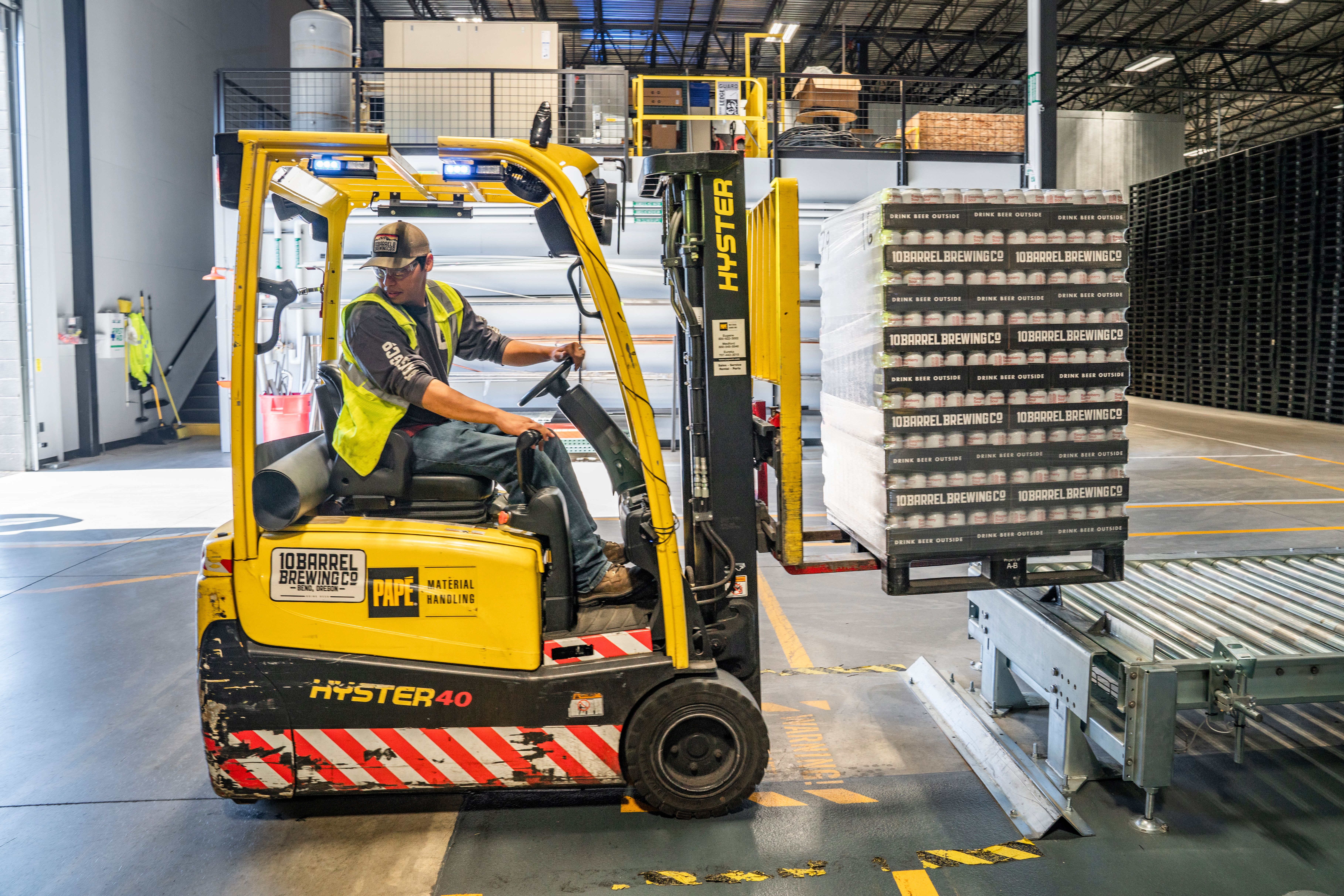 Forklift moving a pallet of goods through a warehouse aisle