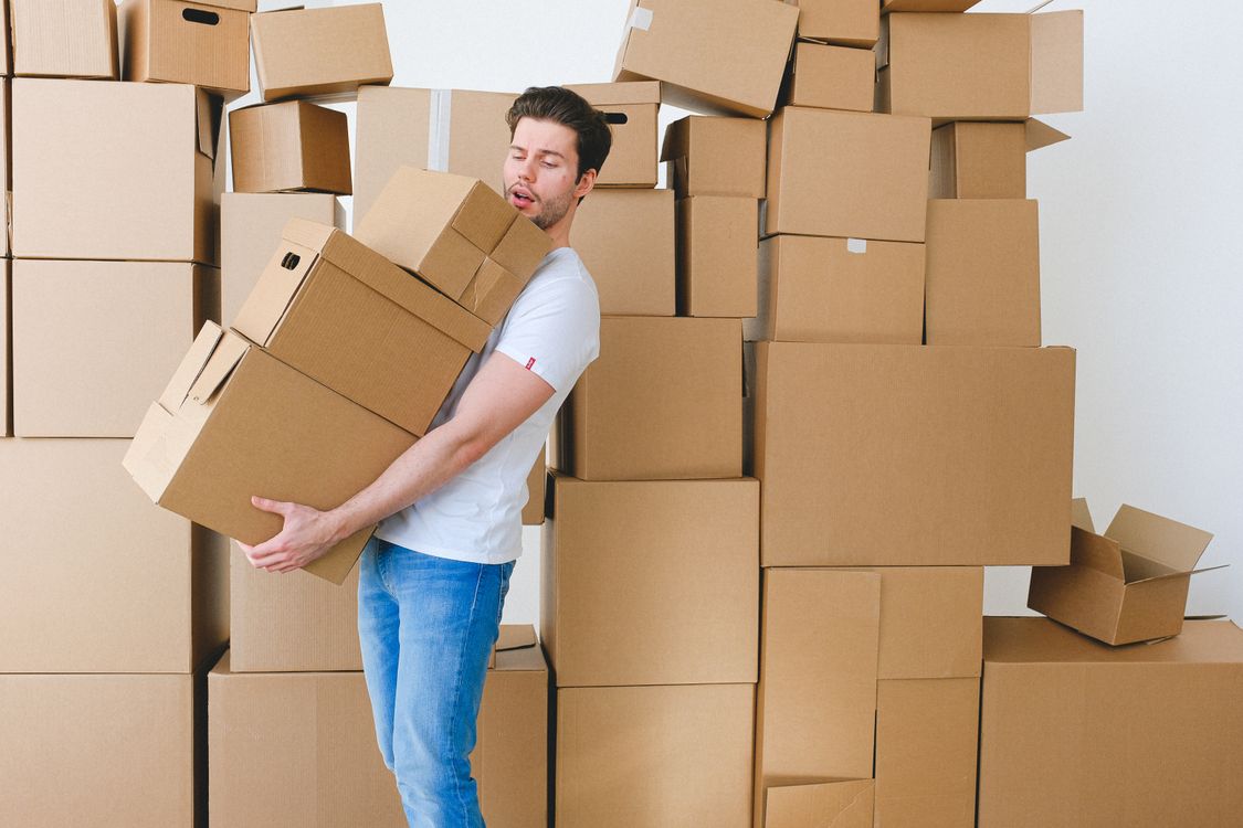 Young man carefully carrying a stack of cardboard boxes during apartment relocation.
