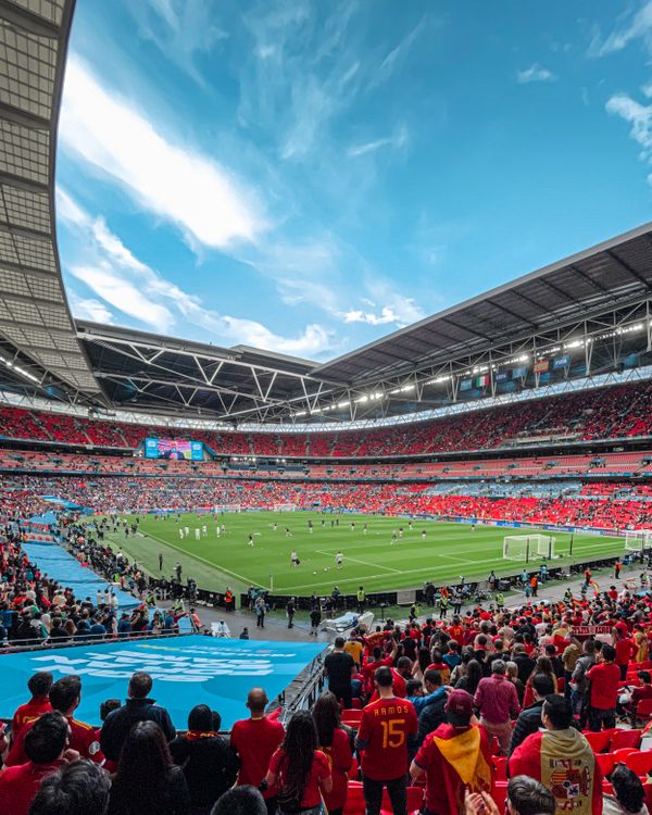 Fans watching a football game in a packed stadium under clear skies