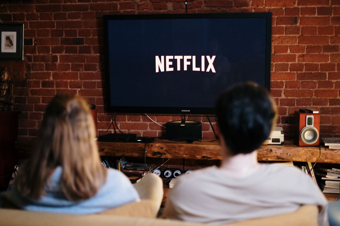 Two people relaxing on a couch watching a movie on television