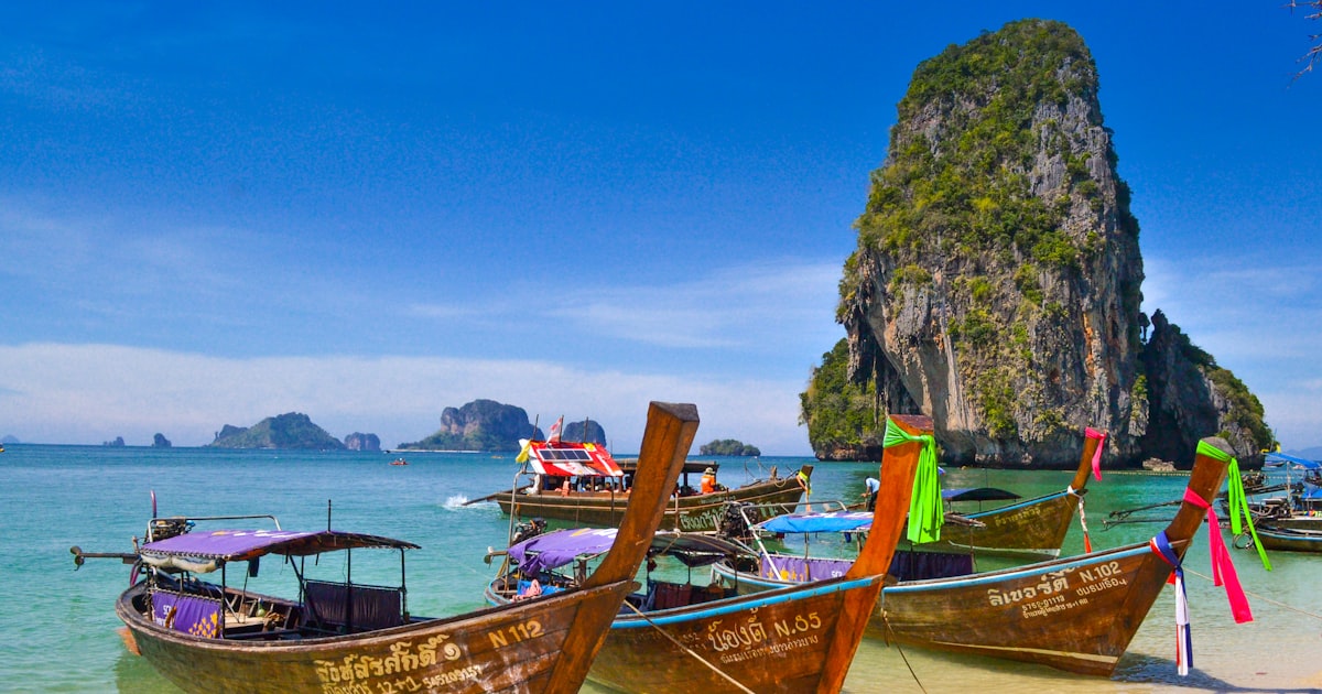 Turquoise water and long-tail boats along a Phuket coastline near a resort area