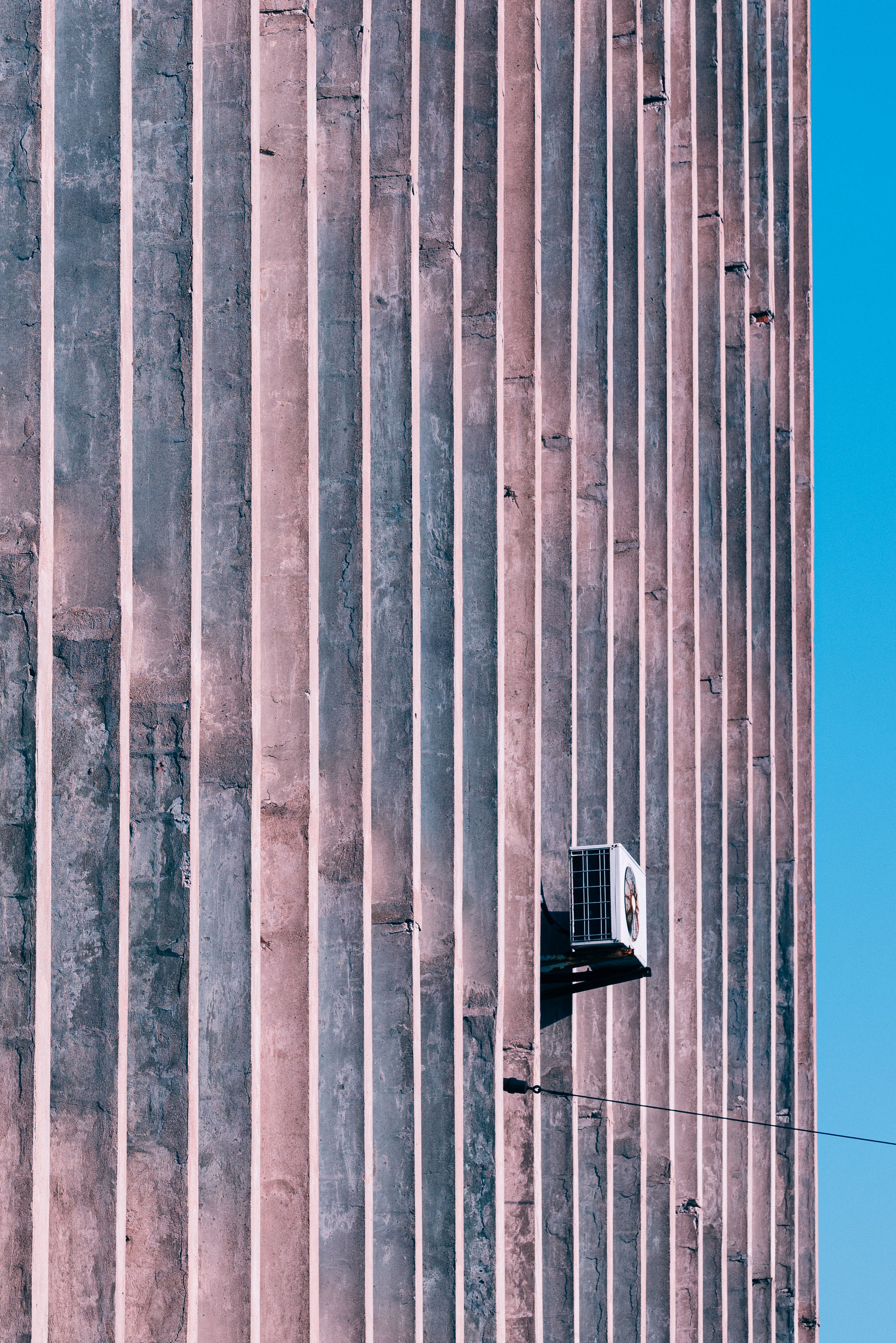 Air conditioner outdoor condenser unit mounted on an exterior building wall