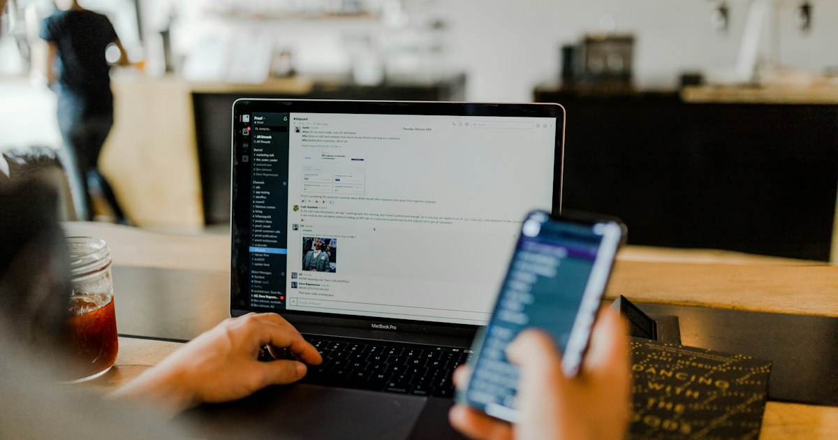 Person using a laptop and smartphone to manage social media pages