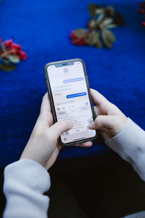 Hands typing on a smartphone to reply to social media comments