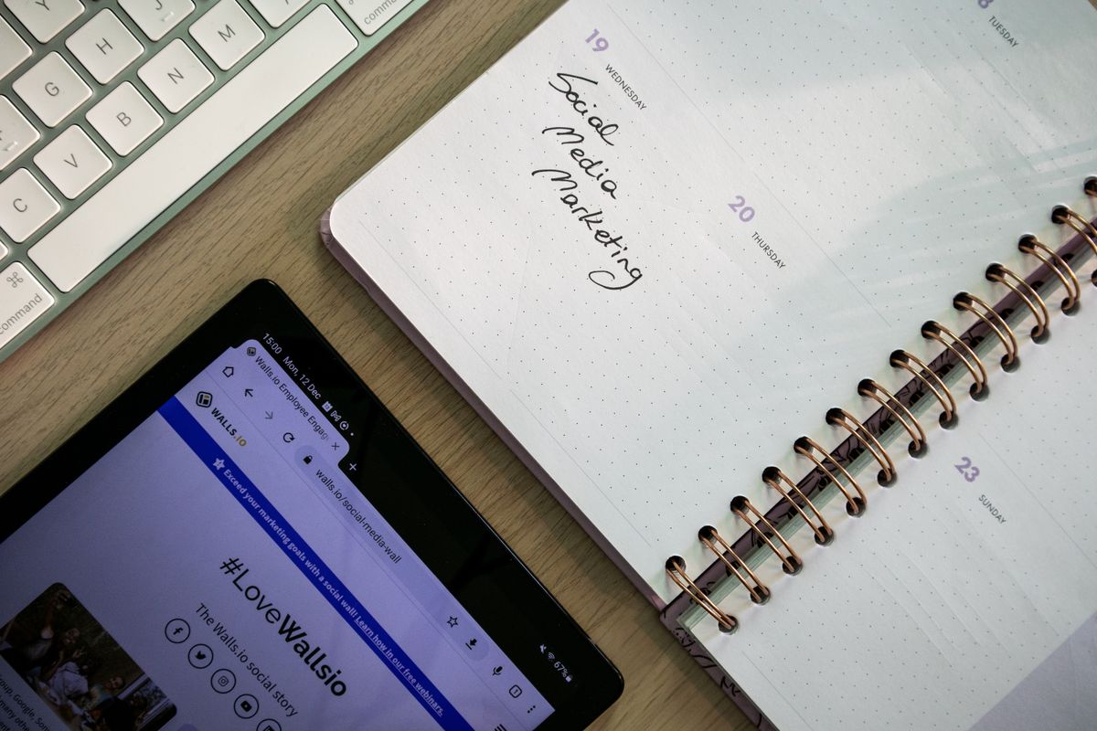 Top-down view of a tablet, notebook, and keyboard on a desk for marketing planning