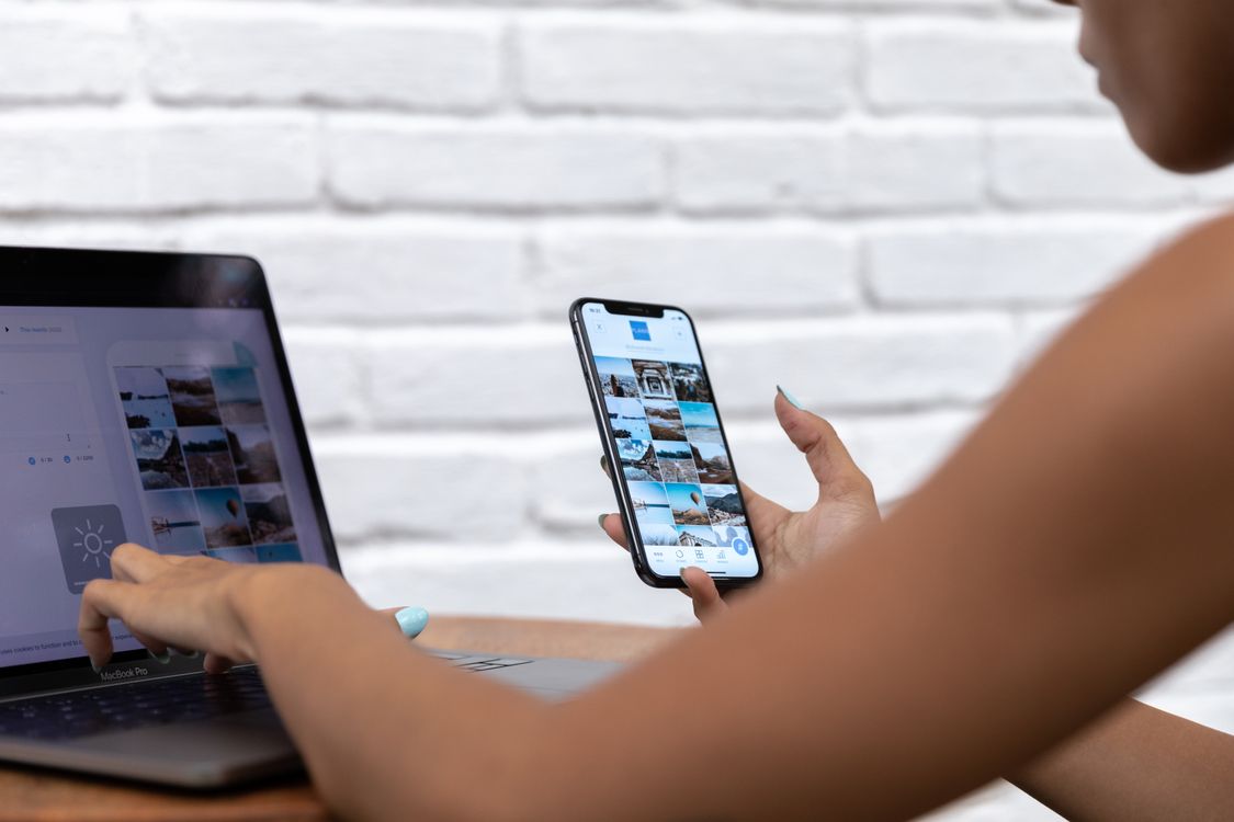 Woman managing social media on laptop and smartphone at desk
