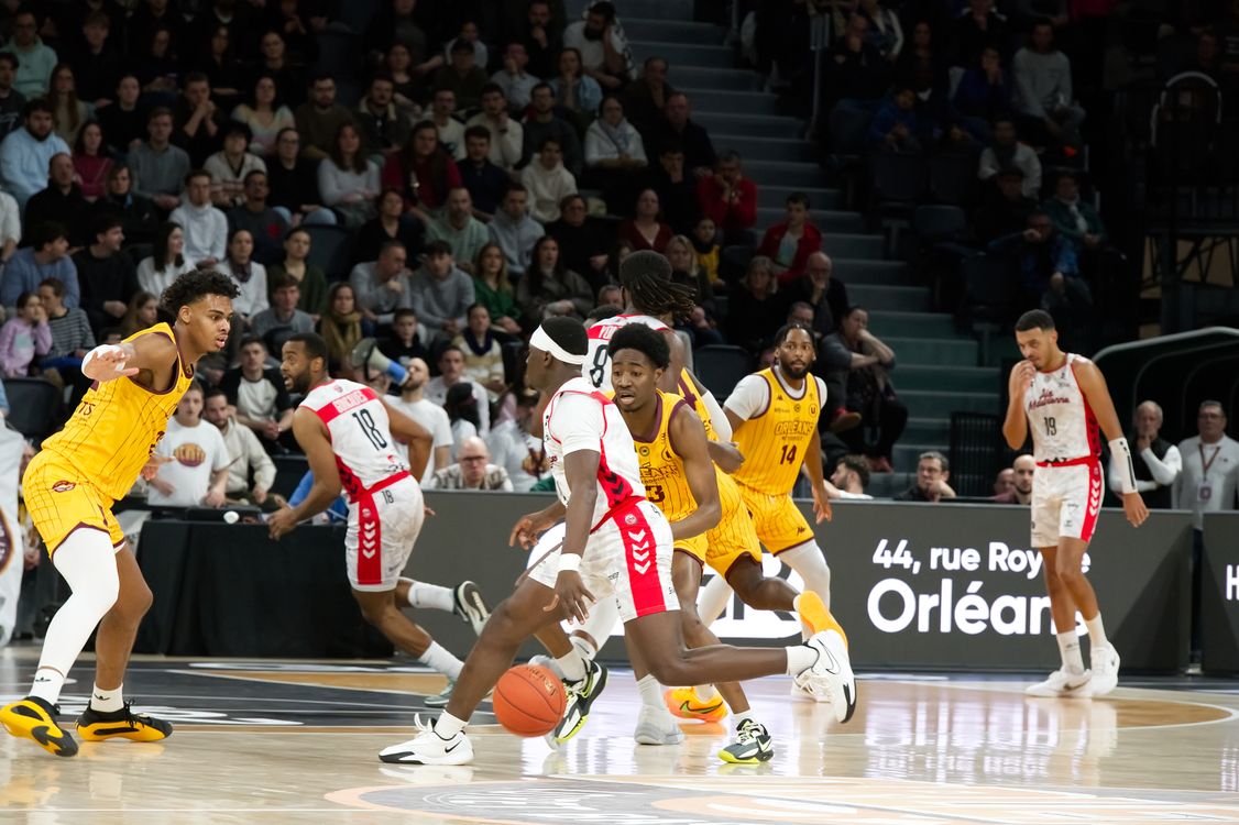 Basketball players competing in a fast-paced indoor arena game