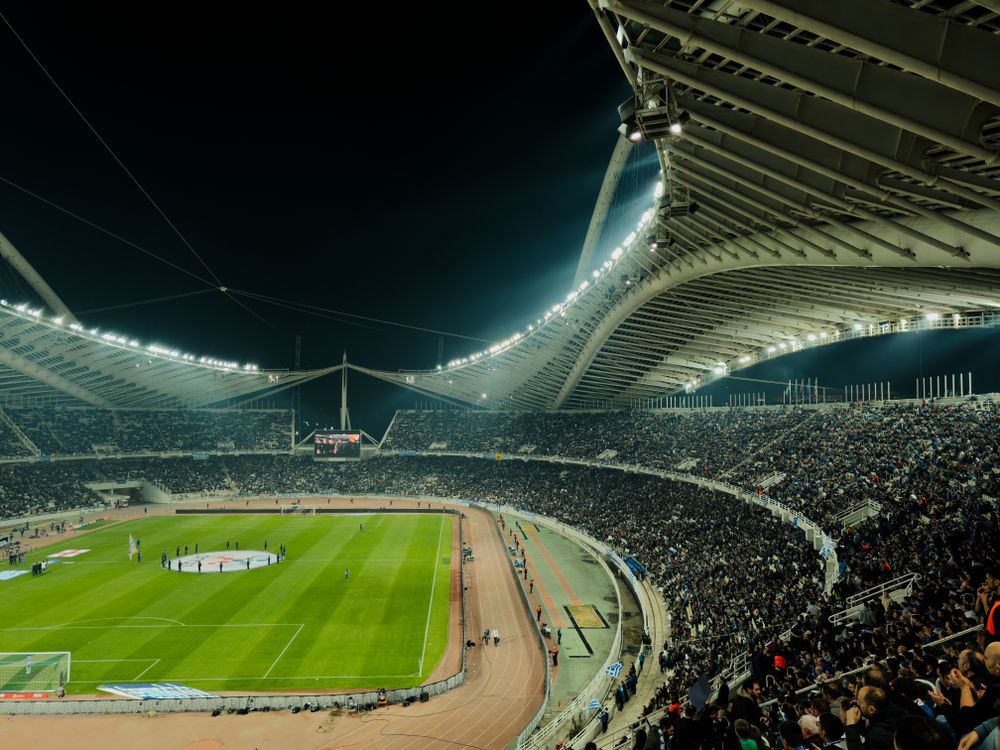 Illuminated soccer stadium at night with a crowd of enthusiastic fans