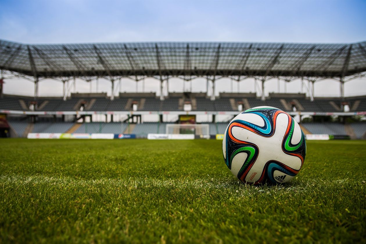 Football on a floodlit pitch inside a stadium