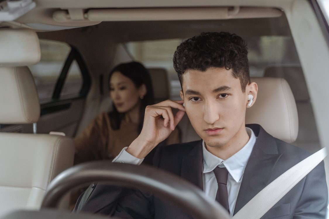 Professional chauffeur in a black suit driving a passenger in a luxury vehicle