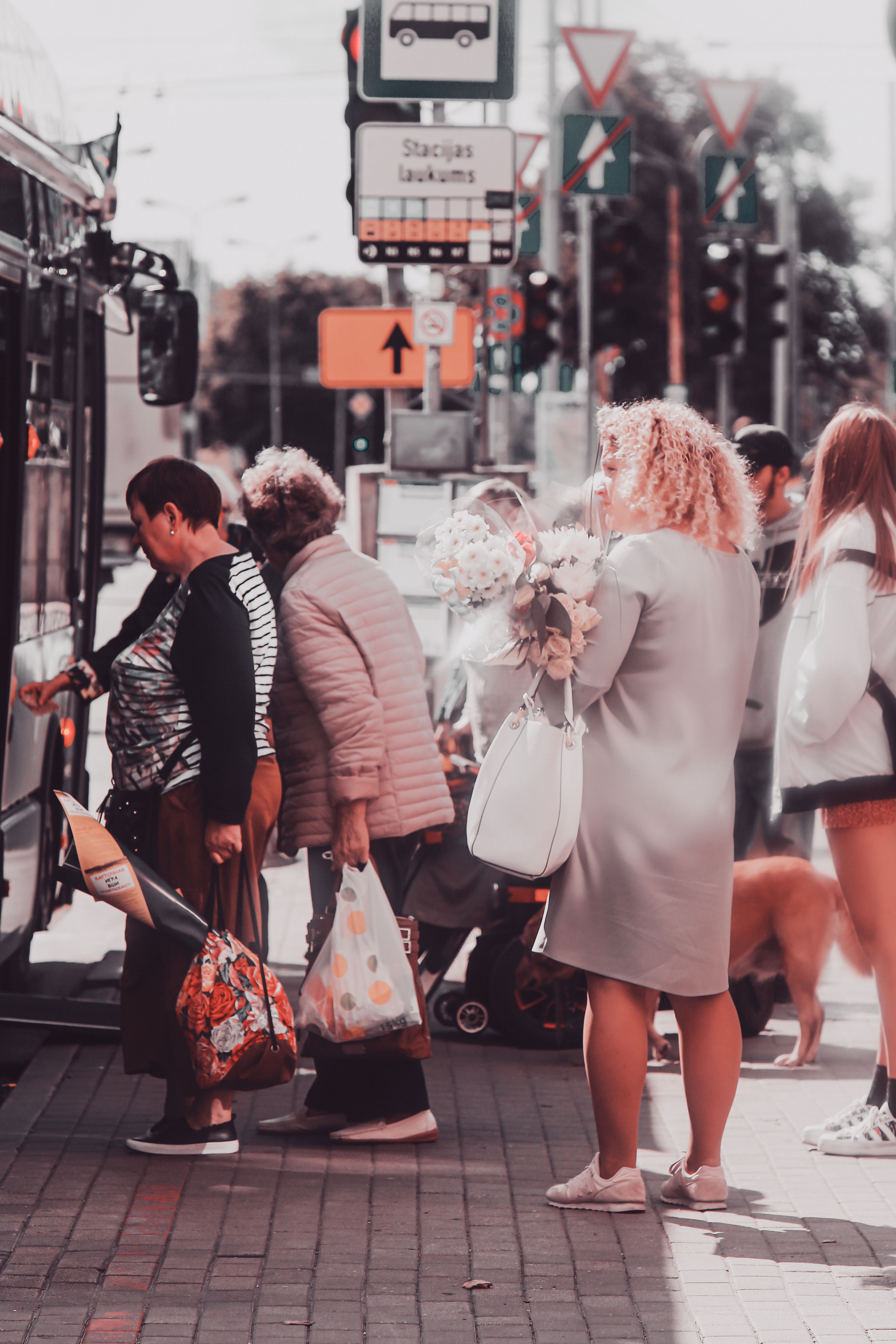Passengers boarding a bus at a city street stop with bags in hand