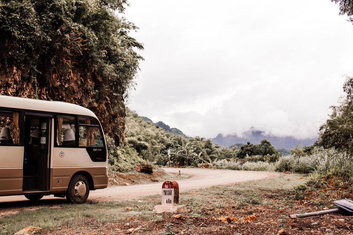 White shuttle bus on a scenic road representing airport transfer service