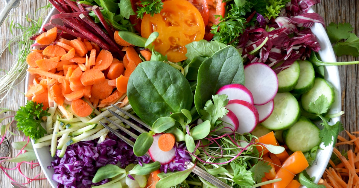 Fresh fibre-rich vegetables including leafy greens and colourful produce on a wooden surface