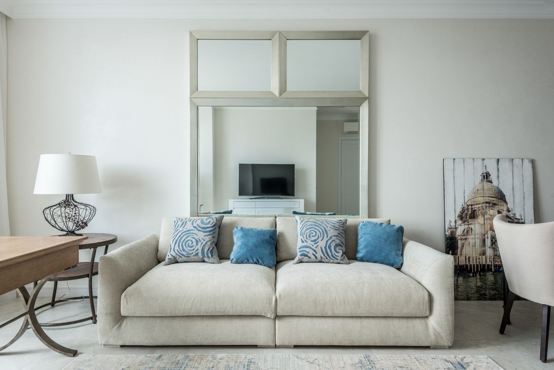 Living room with a beige sofa, layered blue cushions and soft decorative accents