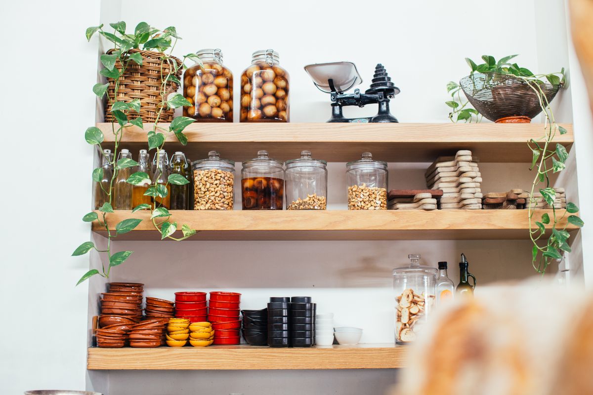 Wooden pantry shelves with organized glass jars filled with dry ingredients and spices