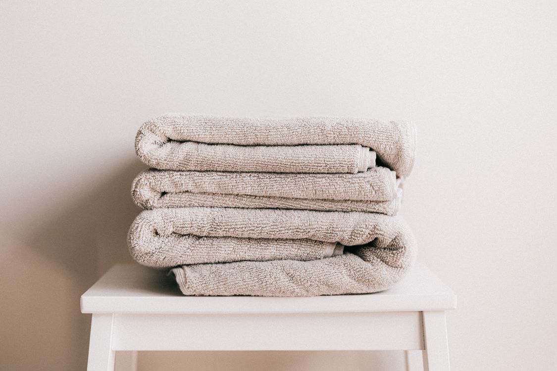 Folded beige towels stacked on a stool