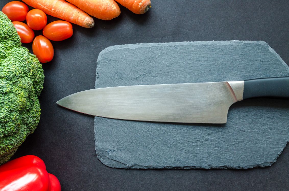 Fresh vegetables beside a chef's knife on a board