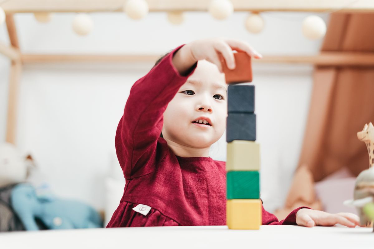 A young child playing with colorful wooden building blocks on the floor