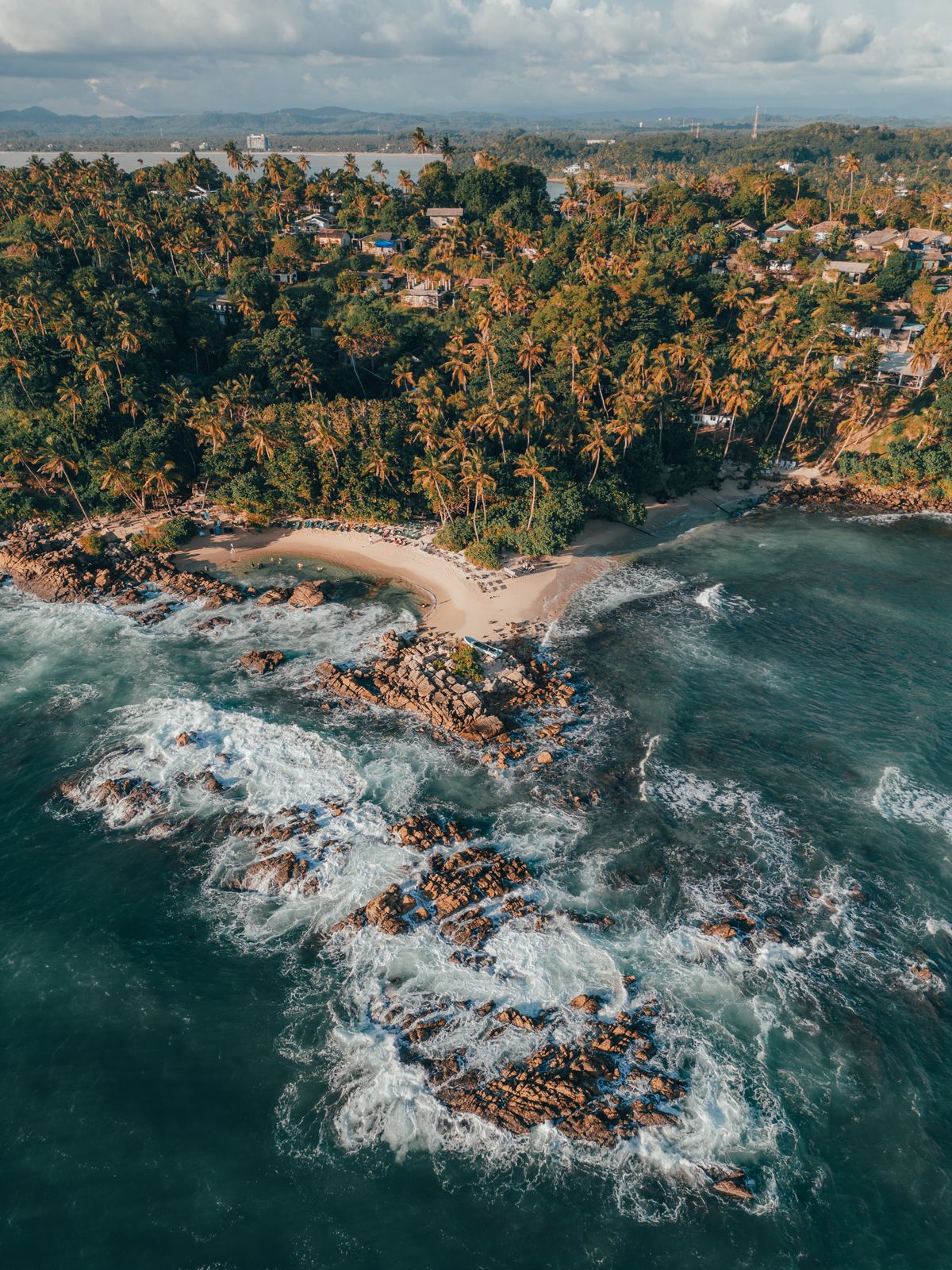 Aerial view of Mirissa Beach with turquoise water and a palm-fringed coastline on Sri Lanka's south coast