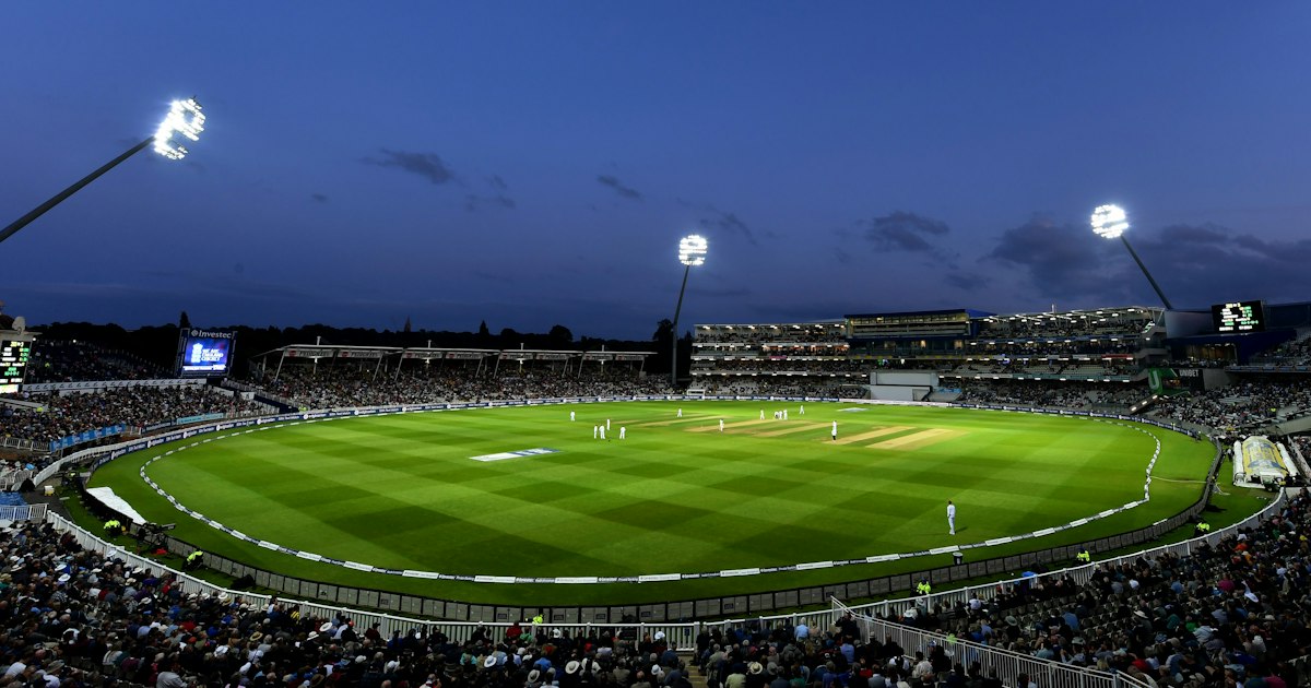 Cricket match in progress on a green field with players in position