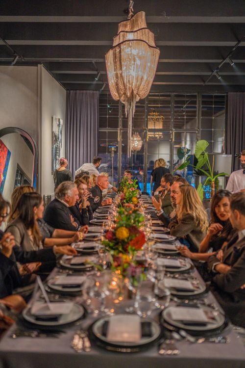 Elegantly dressed guests at a formal corporate gala dinner with elaborate table settings