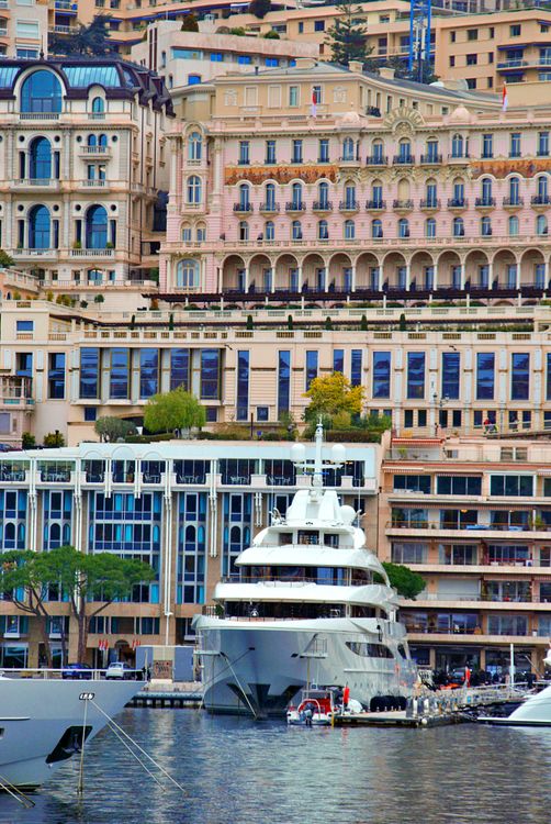 Luxurious yacht docked in Monaco's scenic harbor with waterfront buildings in the background.