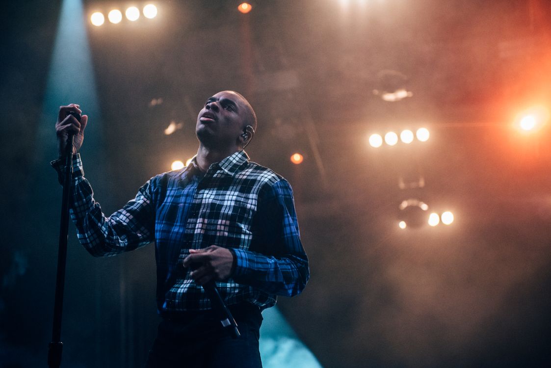 Performer holding a microphone on a lit concert stage
