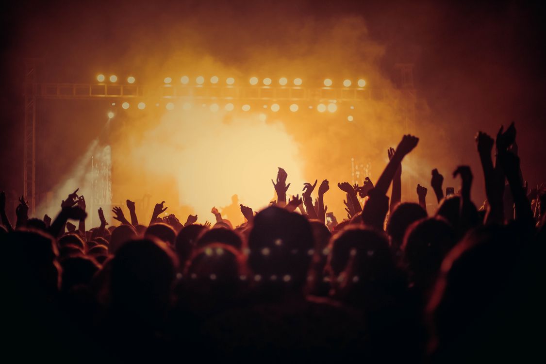 Energetic concert crowd cheering under bright stage lights at a live music performance