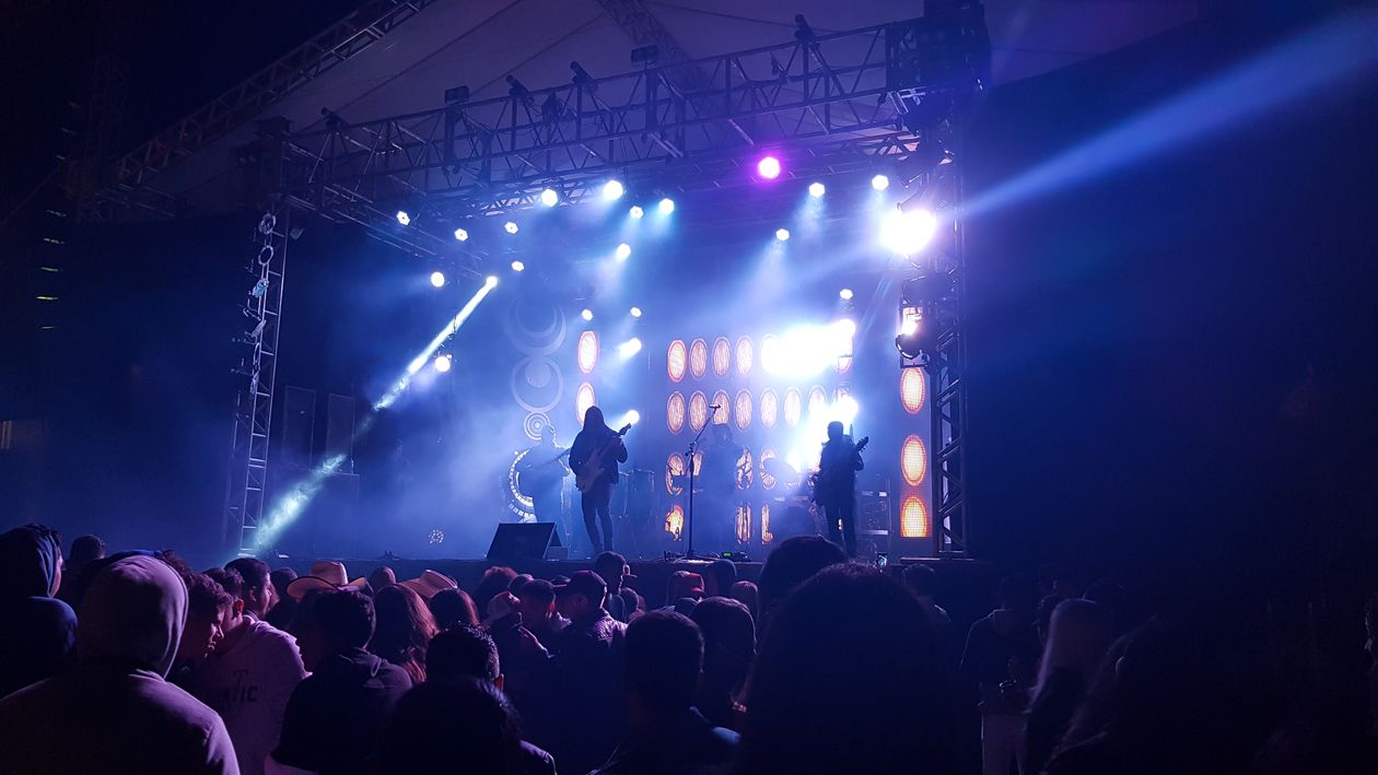 Live band performing on stage to an energetic crowd at a nighttime music event.