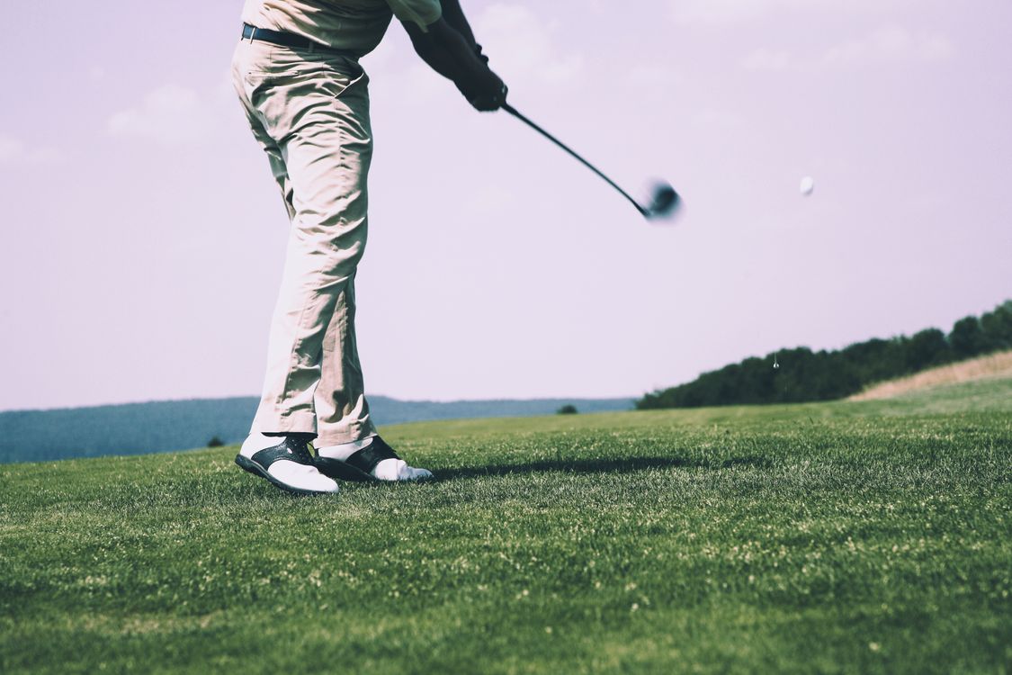 Golfer in mid-swing on a sunny golf course