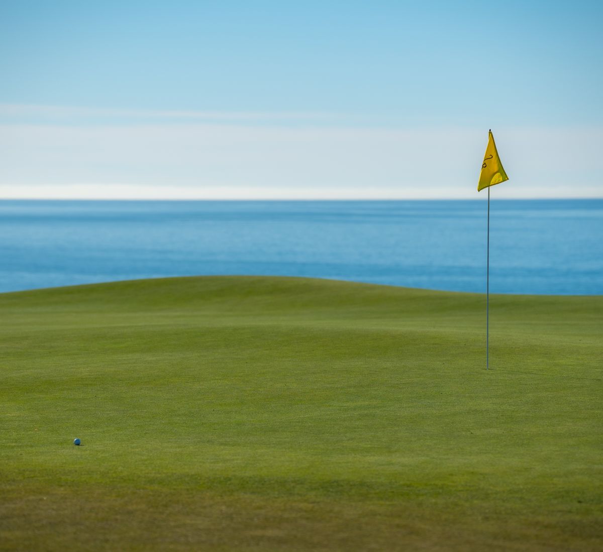 Golf green overlooking the ocean under clear skies on a tropical island course