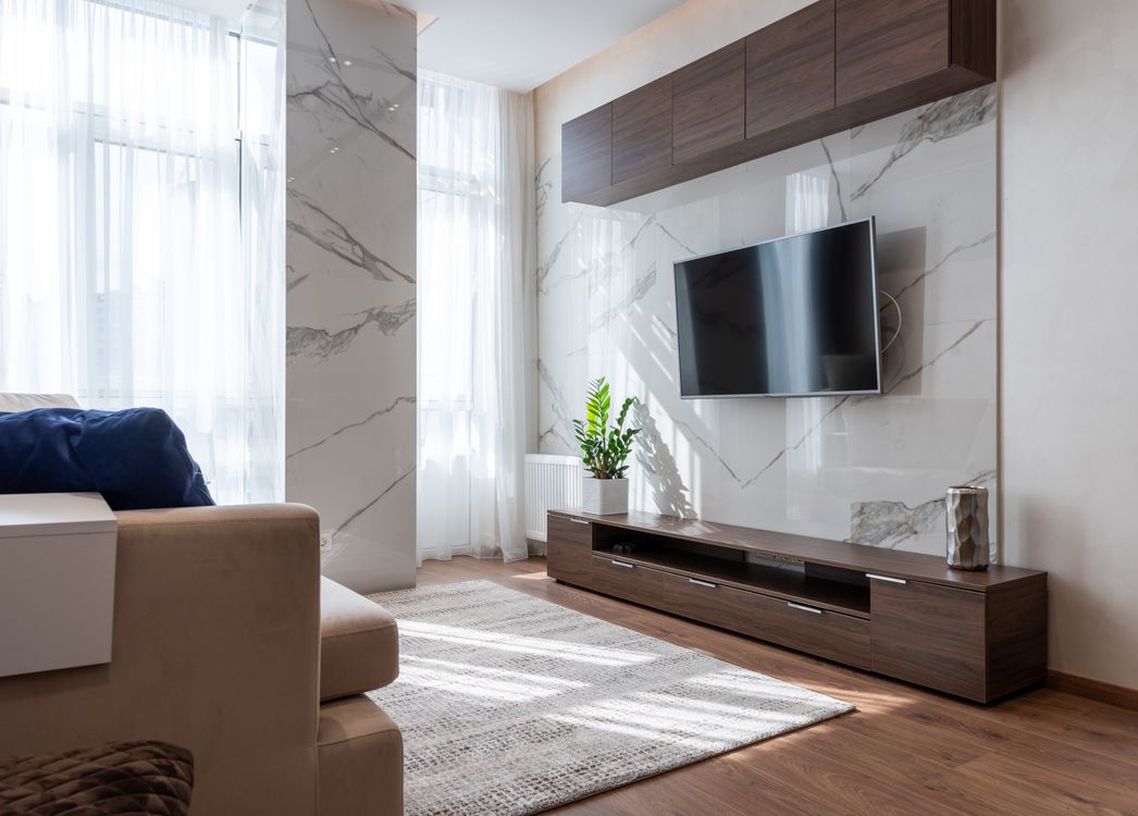 Living room with wooden furniture and a modern couch against a marble wall
