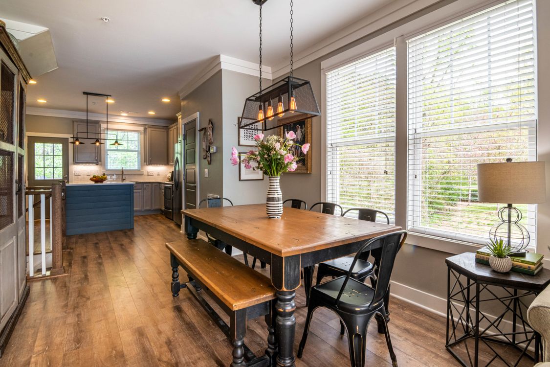 Modern wooden dining table with chairs beside large windows in a bright contemporary dining room