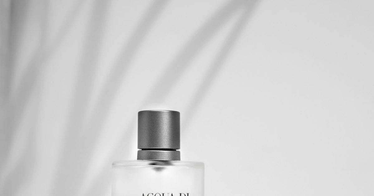 Flacon de parfum en verre entouré de fleurs, évoquant la parfumerie orientale