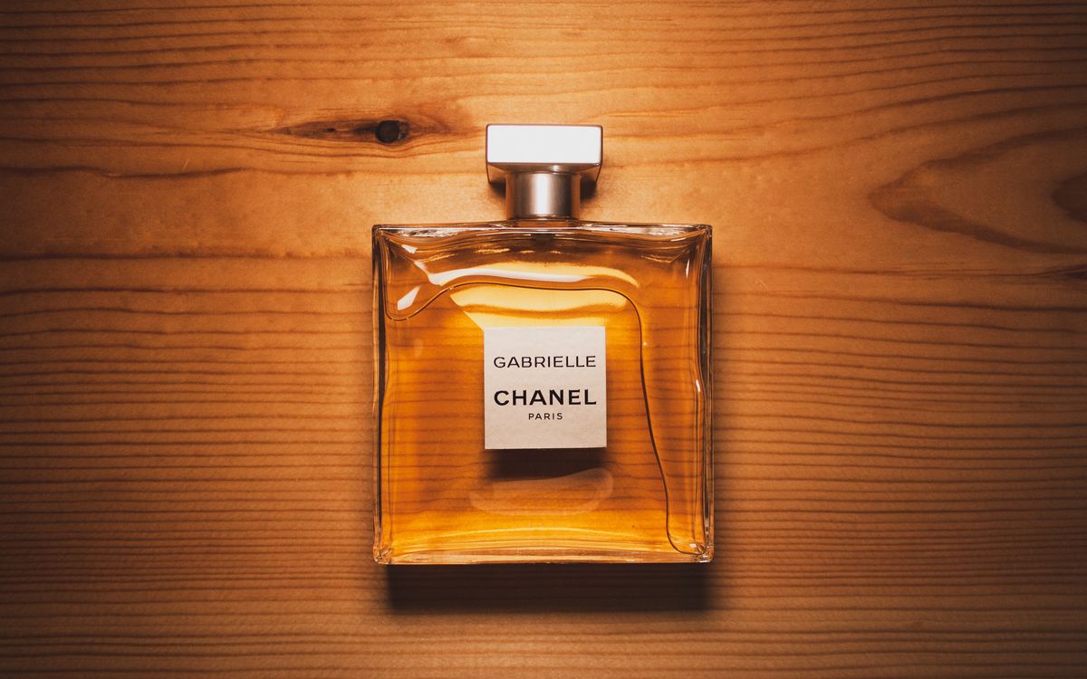 Flacon de parfum en verre transparent posé sur une surface en bois chaud