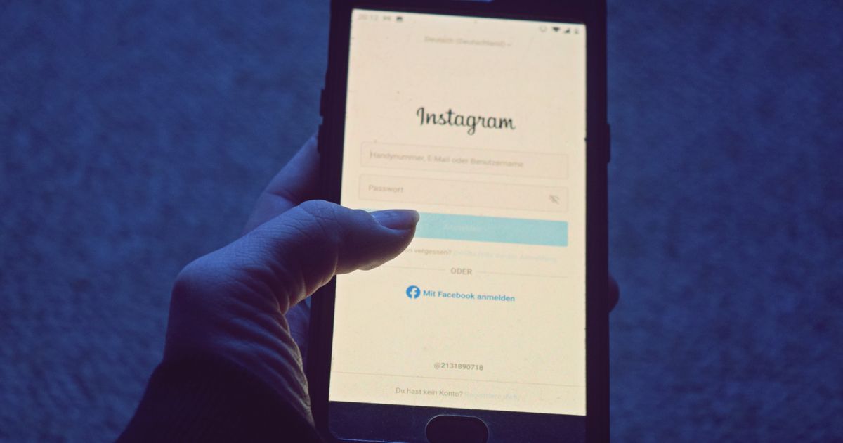 A person holding a smartphone showing a social media login screen