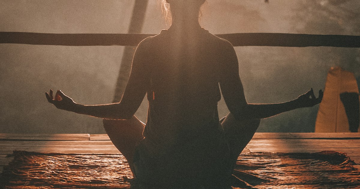 Mujer meditando al amanecer frente al mar