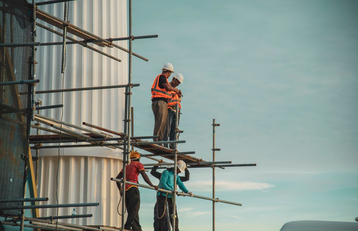Trabajadores en andamios frente a un edificio en construcción