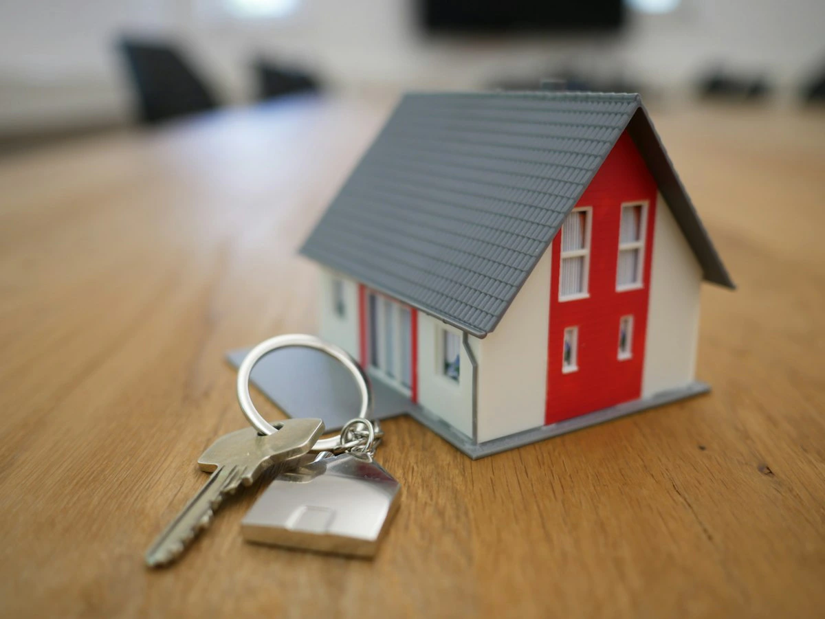 Maquete de casa com chaves sobre a mesa, representando a venda de um imóvel
