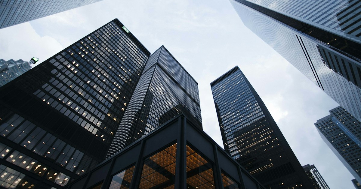 Prédio comercial moderno com fachada de vidro refletindo o céu